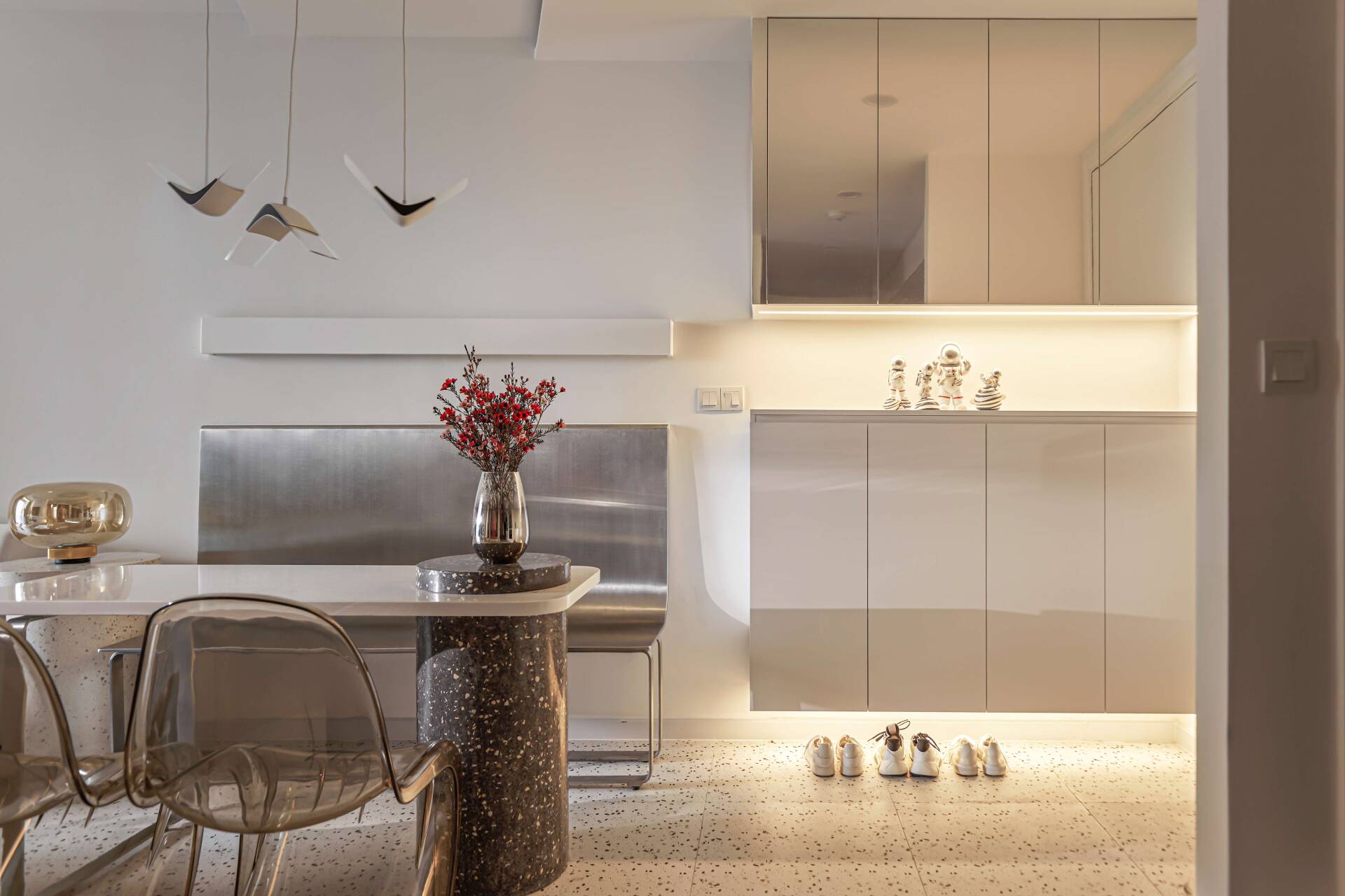 Beside the dining table, the owner puts a shoe cabinet and a system of recessed lights.