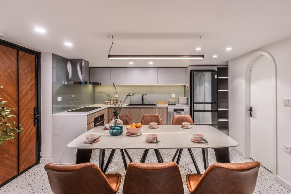 The kitchen is orderly and comfortable with full of necessary facilities inspiring delicious meals. The big white upper cabinets and wooden color lower cabinets are convenient for owners to store kitchen utensils. This dining area separates effectively between the living room and the kitchen.