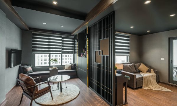 The living room and relaxed room are separated by a wooden wall. On this wall, gold stainless-steel tubes are alternately arranged.