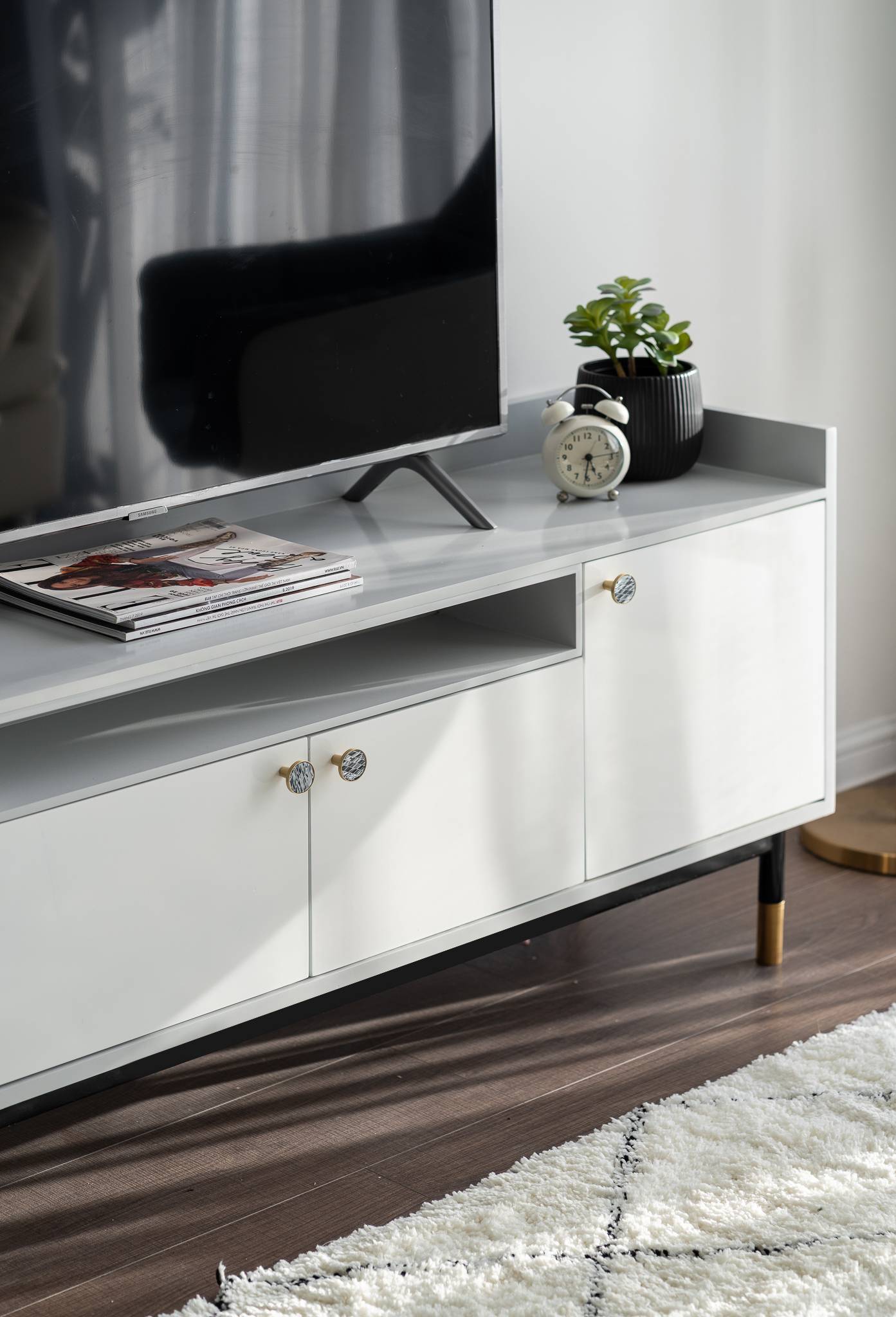 The white TV cabinet combines with a Nordic-style featured wool carpet