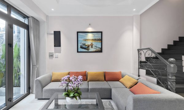 Living room is simply decorated with an L-shaped sectional sofa and a glass coffee table. The taste of sea is taken into this space through an eye-catching picture on the wall.