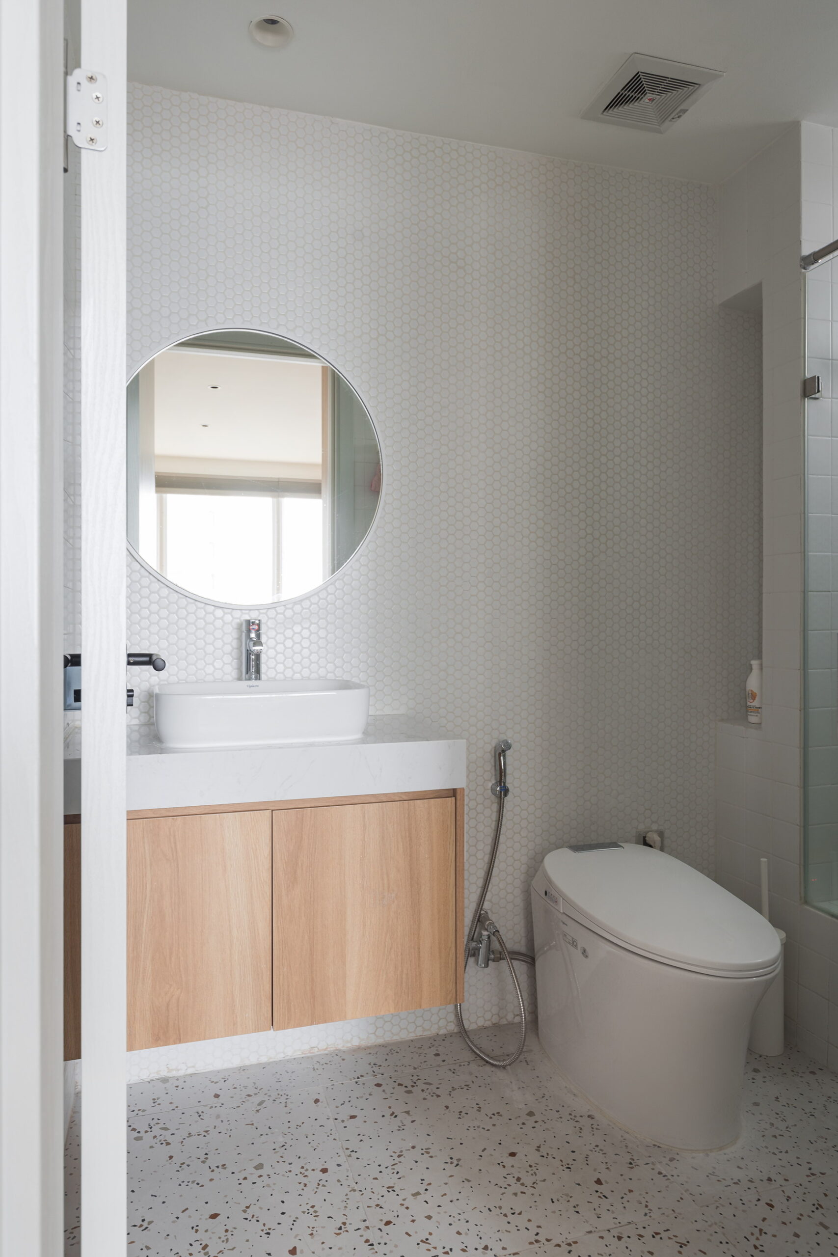 The bathroom uses white mosaic tiles and square tiles, making space more organized, in tune with kitchen tiles.