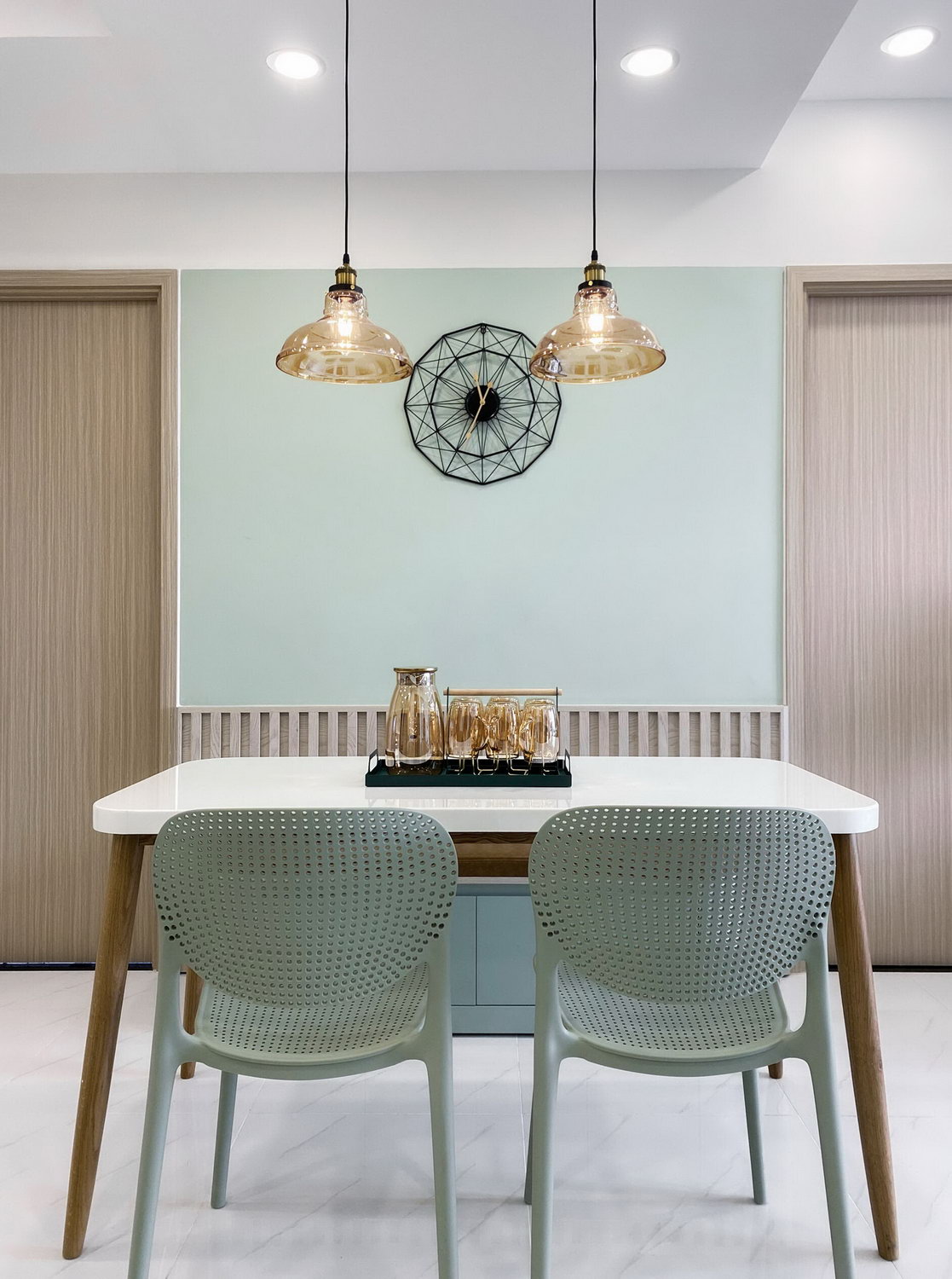 Two pendant lights draw the eye to a stylish black o’clock on the mint wall. 