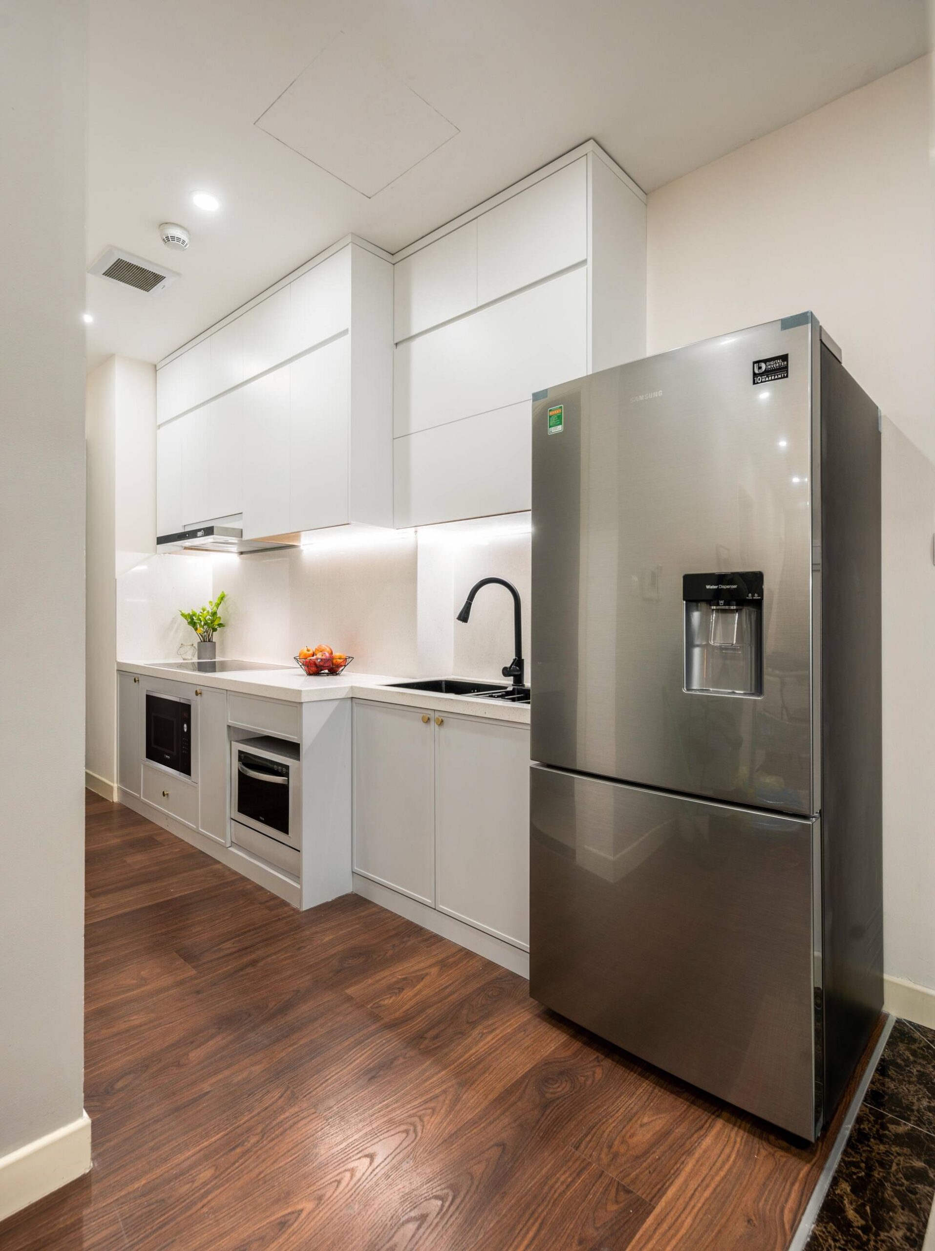 The kitchen uses the main light gray color, contrasting but still in harmony with the brown wooden floor and luxurious gray refrigerator.