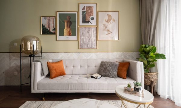 The cream fabric sofa is adorned with small orange and gray pillows that are very harmonious.