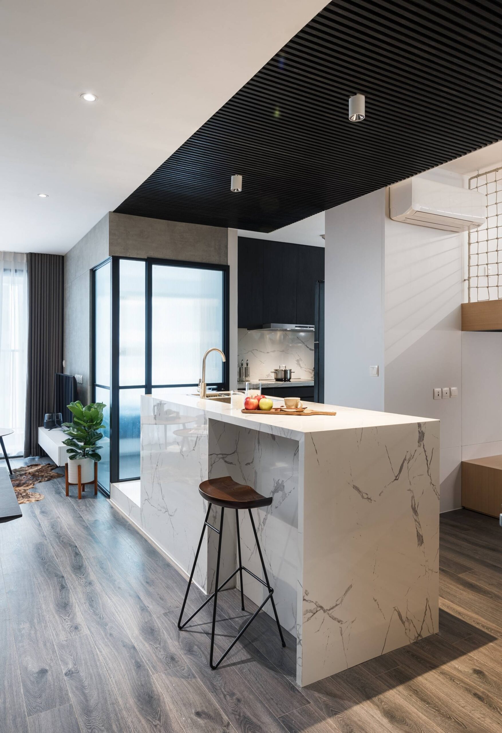 For kitchen area, the architect uses white marble to make a contrast with black wood on the dark gray floor creating a perfect highlight for the whole apartment.