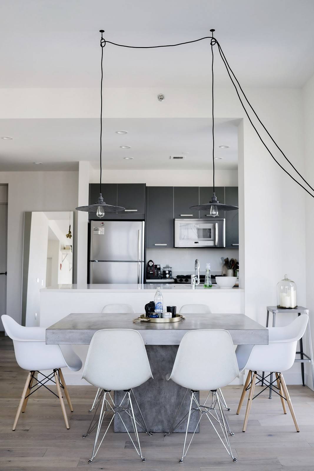 The concrete table with stainless steel chair leg design, pendant lights are the highlights for this kitchen which is neat, simple and clean.