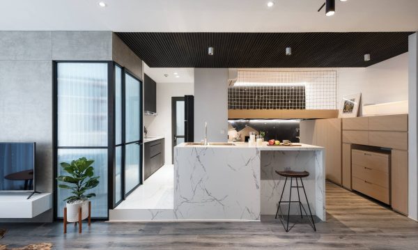 The kitchen is separate, its floor is raised up and the stone material is used in sync with the bar, both helping to divide and create a connection between spaces.