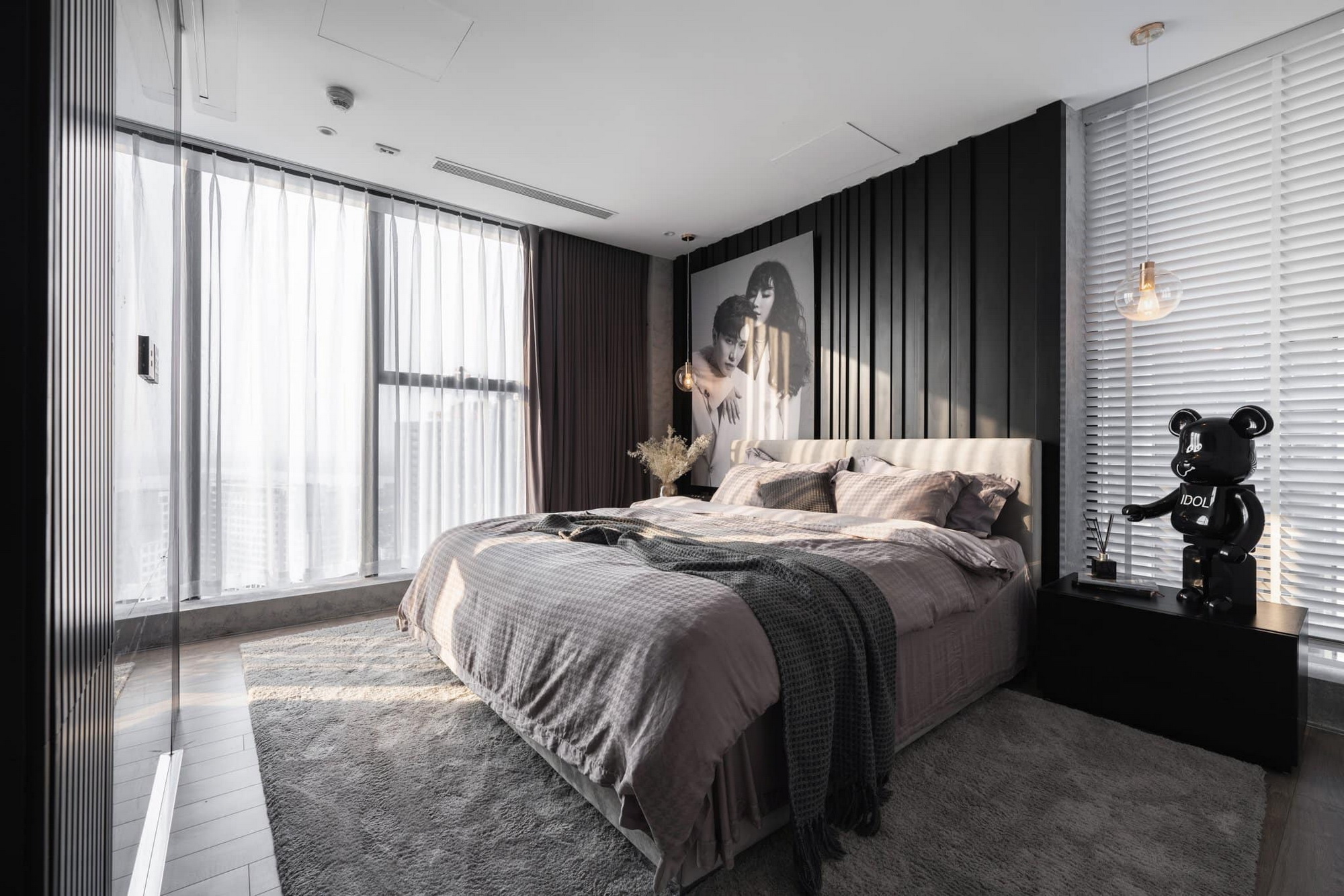 A minimalist bedroom has neutral colors like gray, white, and black, along with a large floor-to-ceiling window to provide needed light. 